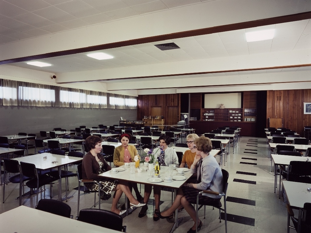 Fem kvinner sitter ved et bord i spisesalen til de ansatte i konfeksjonsfabrikken til Jonas Øglænd AS på Sandnes.