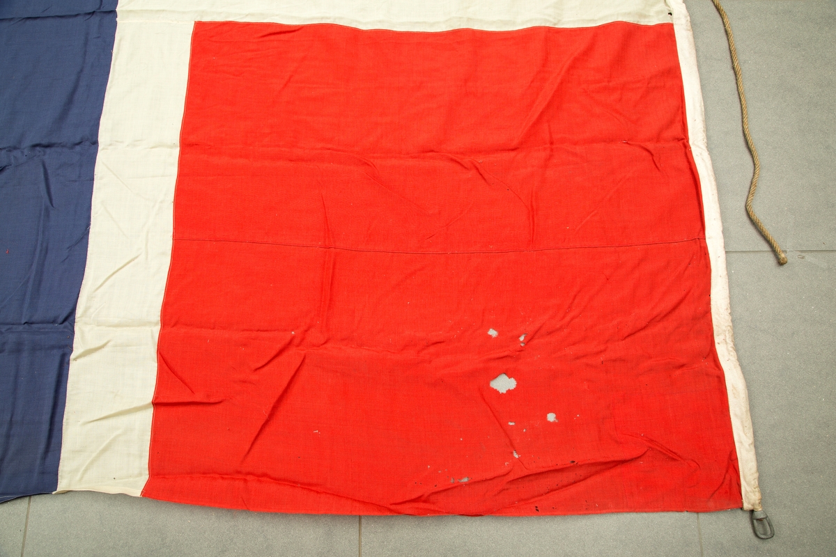 Flaggpose med flagg. A) pose i jute med tau. B) norsk flagg, meget slitt i enden motsatt stangfestet.