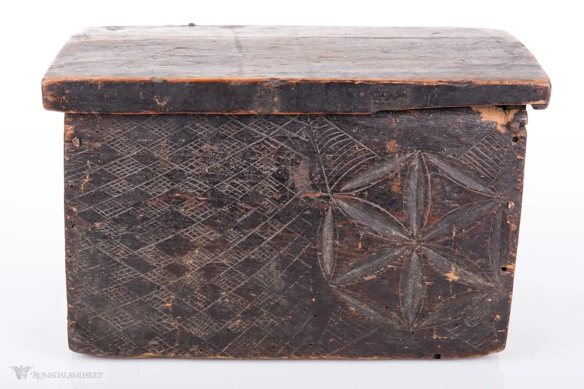 Seksbladsroser i karveskurd. 2 bak, en i front og en på hver korside. Rissede dekorfelt omkranser motivene.