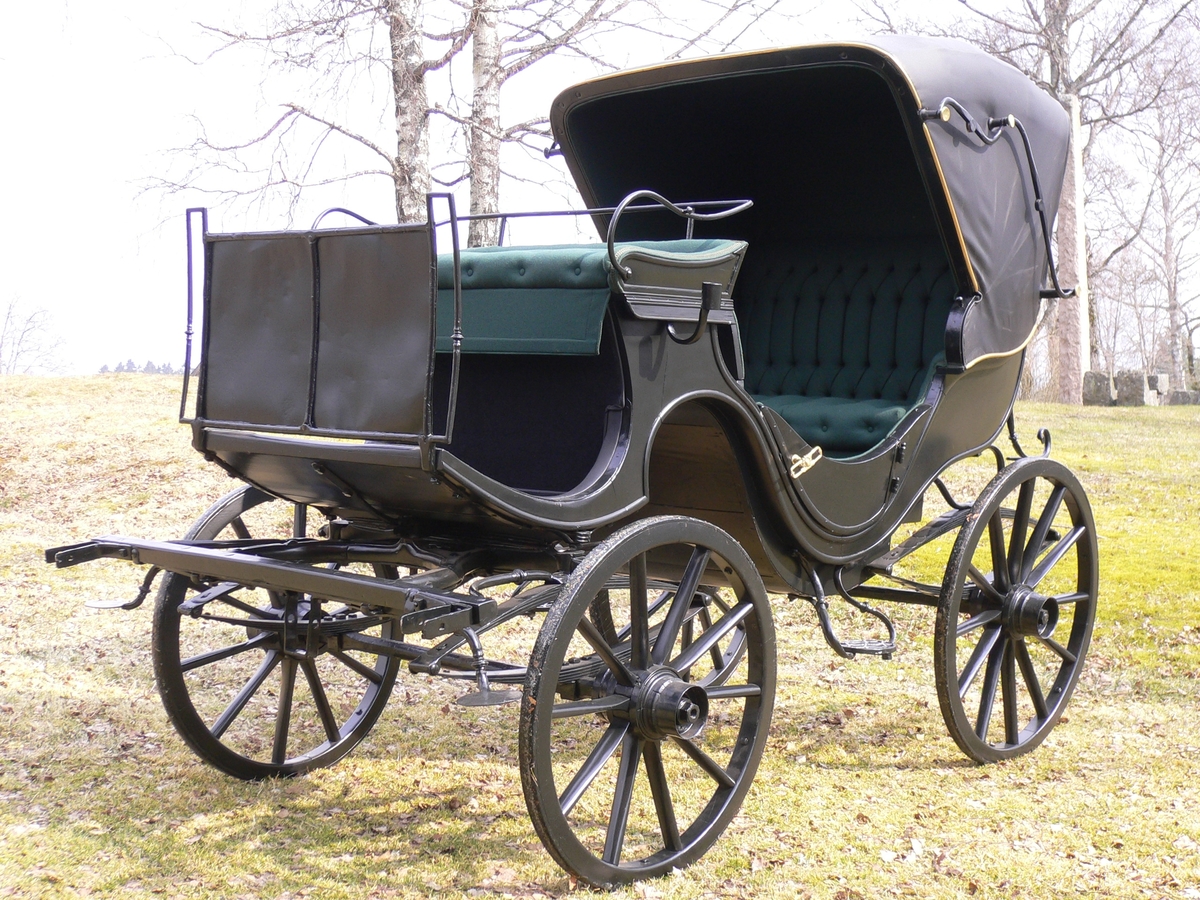 4-hjuls vogn med kalesje for to hester til persontransport. Fast kuskebukk, hovedsete og motsete med lokk. Fast kalesje. To lave dører.