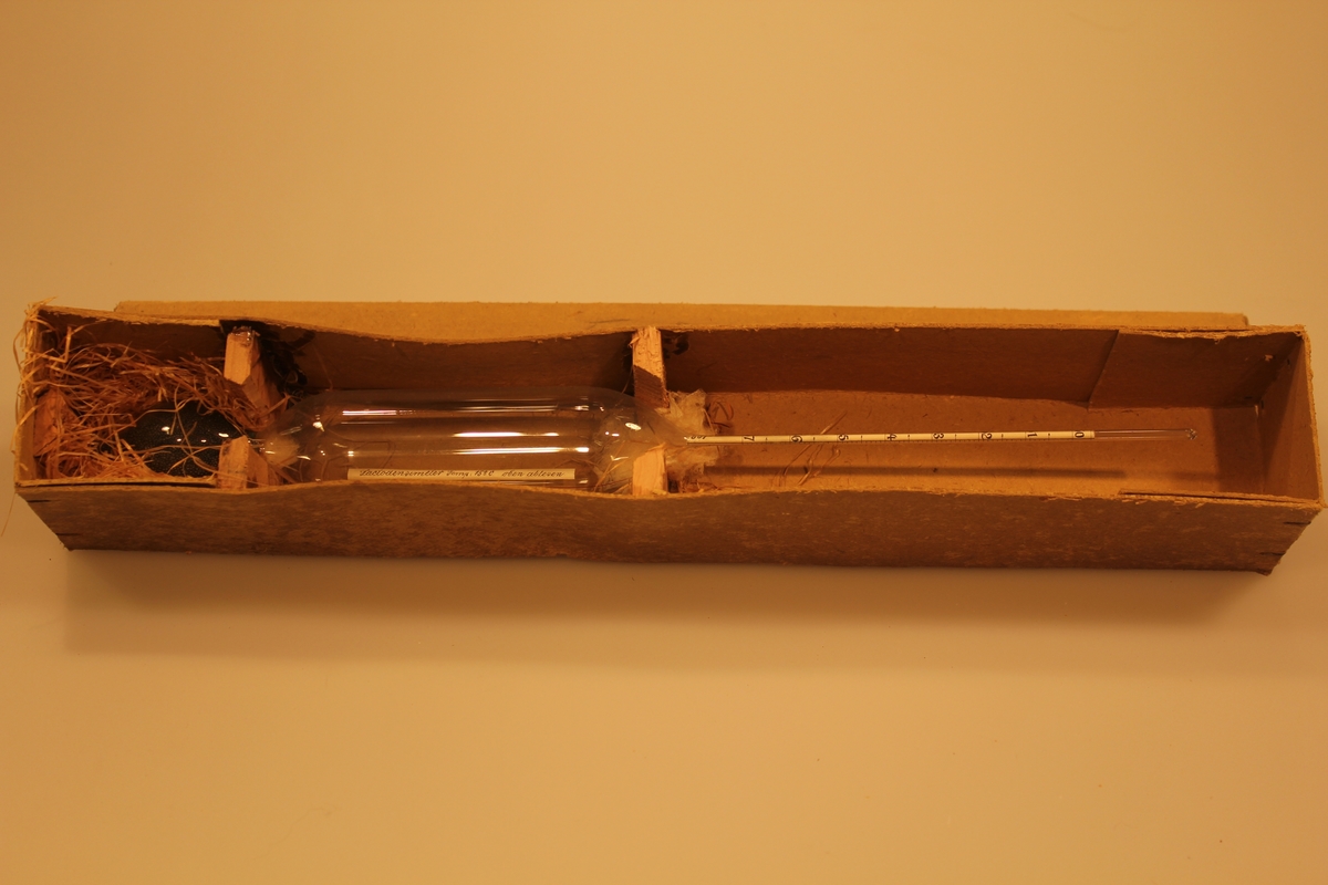 Måleinstrument for verdier i melken ved 15 grader. Det har en sylindrisk form med innsnevring to steder. Instrumentet ligger i original embalasje.