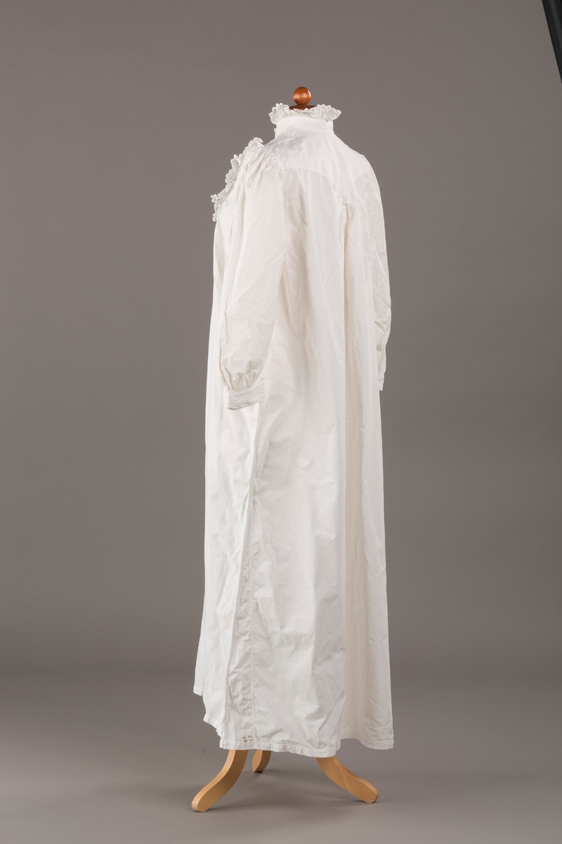 Form: Lange ermer, fotsid.

Blondekant og rysjer i halsåpning.
To knapper i metall kledd i tekstil. Mangler en knapp.