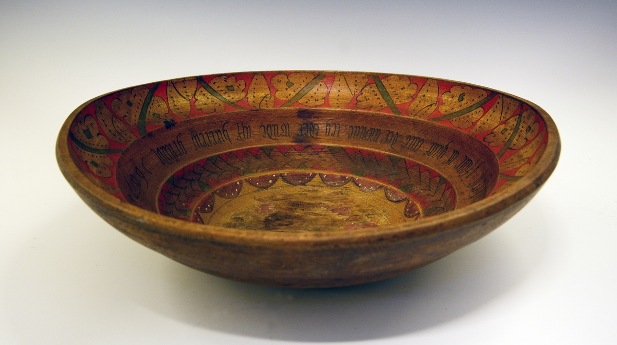 Ølbolle. Fra protokollen: Ølbolle, stor, flaagjord, svarva med 3 ribbar inni. Kromgult maala, og inni maala rosur i raudt og grønt med svart kontur og skrift. I botnen eit slag rosur, no mest burtsliten, og til borde rundt kanten eit bandsegment. I fyrste ribbe ei "myntsnor" av gule rosur, som stend paa .... I næste ribbe denne innskrifti med haag smal (minuskelsvipande) fraktur: in ij denne skaaell en Rosem Staar min hiertenskierist ij faar itt gaat aar det wonnne ieg eder ?nde aff hiertens grunde 1607. Ytste og øvste ribbe hev paa raud botn eit grønt lokastig band med gule blad og knuteformur i tidsens mynster. Under botnen stend paa 2 stadar bumerket Y utskori.