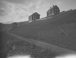 Gård med to store hovedbygninger oppe i dalsiden.