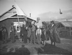 Gruppe mennesker utkledd ved hus.