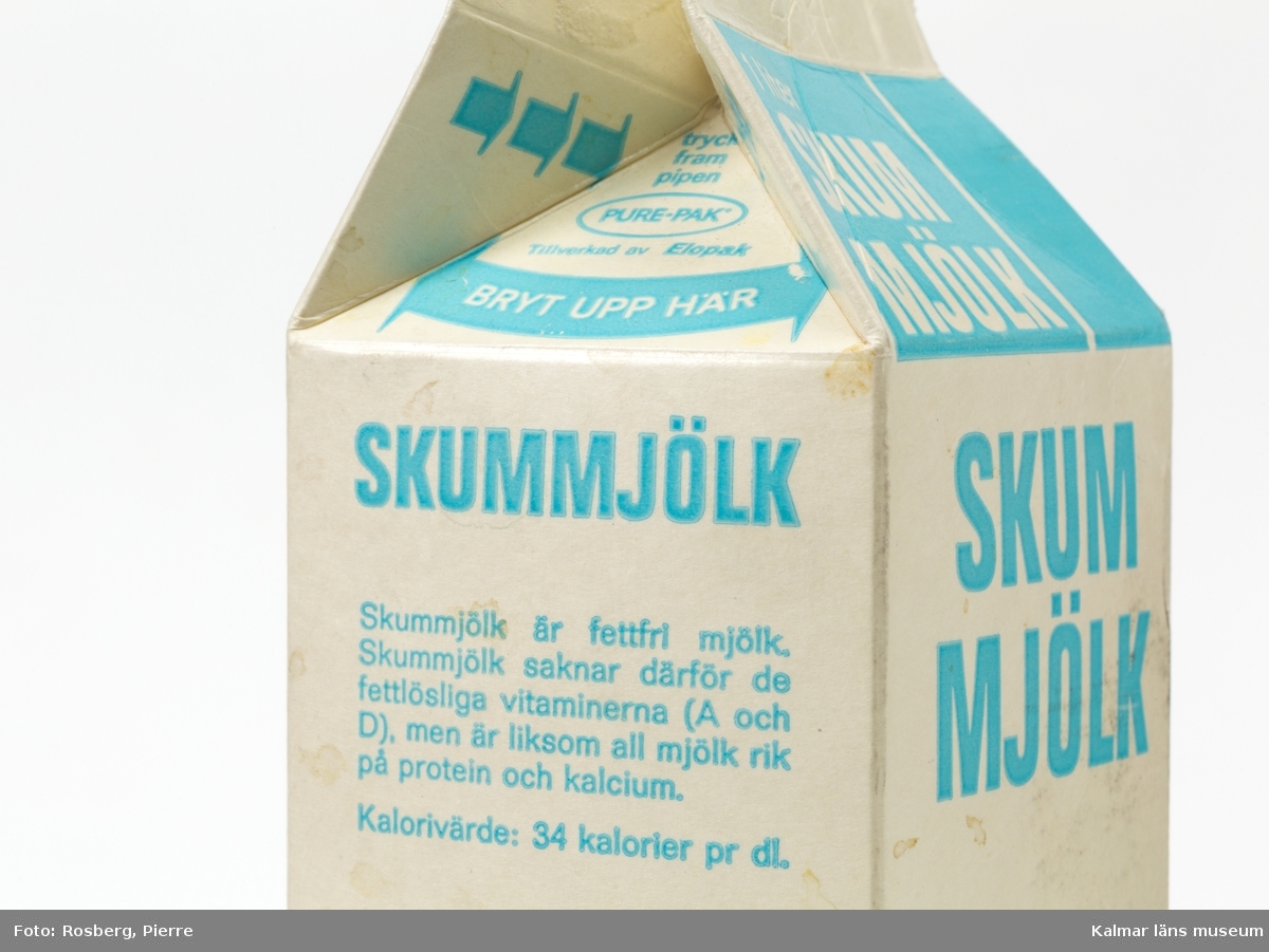 KLM 45273:1 Förpackning, mjölkpaket, pappkartong. Pure-pak, av vaxad papp. Text och dekor i vitt och ljusblått. På övre delen, två av sidorna, texten 1 liter skummjölk. På sidorna texten skummjölk på två av sidorna, på en sida texten ”Kalmar mejeri  Datummärkningen anger sista rekommenderade försäljningsdag. Från denna dag håller sig produkten i oöppnad förpackning ytterligare ca 4 till 5 dagar vid förvaring i kylskåp (5-7°C)”, på en sida texten ”Skummjölk är fettfri mjölk. Skummjölk saknar därför de fettlösliga vitaminerna (A och D), men är liksom all mjölk rik på protein och kalcium. Kalorivärde: 34 kalorier pr dl”. På var sida en fyrklöver som dekor. Den övre delen av förpackningen har öppnats helt för att kunna rengöra den men kan återställas så att den ser oöppnad ut eller öppen för att hälla upp.
