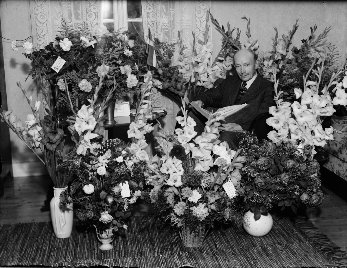 Man i bostadsmiljö omgiven av blommor, Östhammar, Uppland
