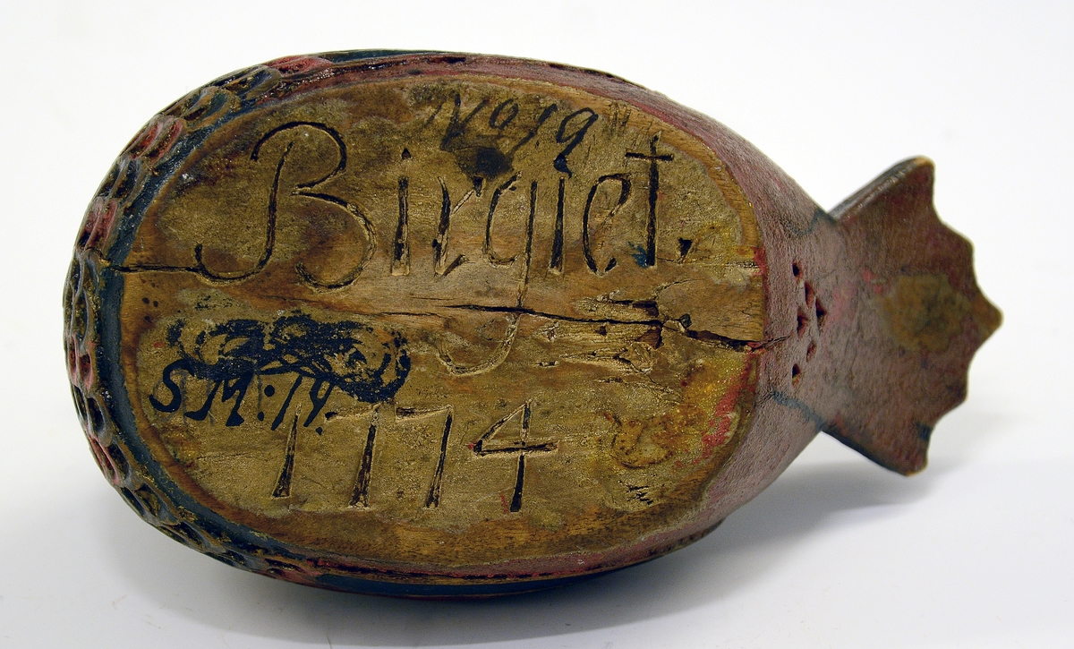 Ølhøne. Fra protokollen: Koks, liten og høneformet, malt. Hovedet kort, med kam, brystet skaaret i fjærskjæl, siderne i vinger, halen kerbsnit. Under skaaret "Birgiet 1774". Malt i rødt og blaagrønt, gult indeni.