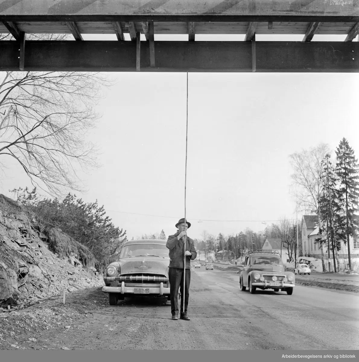 Sjølystveien.Ny gangbru over Sjølystveien..Tung-transportmannen L. Sandvik i Transportsentralen fortviler over at brua har for lav høyde over veibanen..Mars 1962