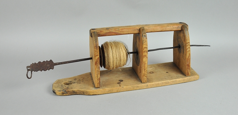 Snellestol av tre med plass til to sneller. Det er festet tre hyller på en treplate. Snellene festes på en metallstang som er går gjennom hyllene. Hyllene er avrundtet foran, og snellestolen kan festes på veggen.