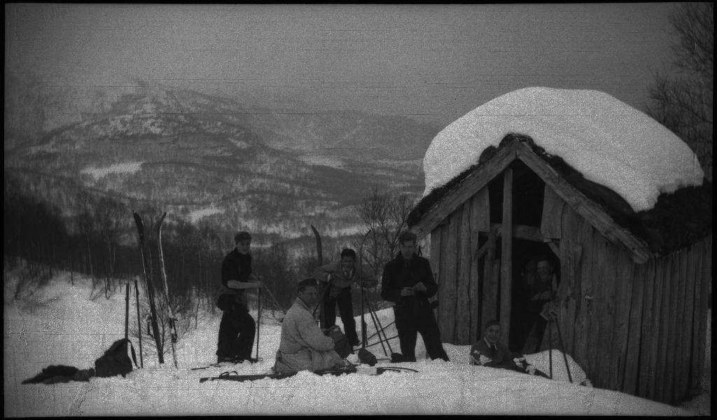 En guttegjeng på skitur i fjellene ovenfor Saudasjøen. Det er bilder av gjengen som går oppover bakkene, og fra en pause ved en gammel hytte.