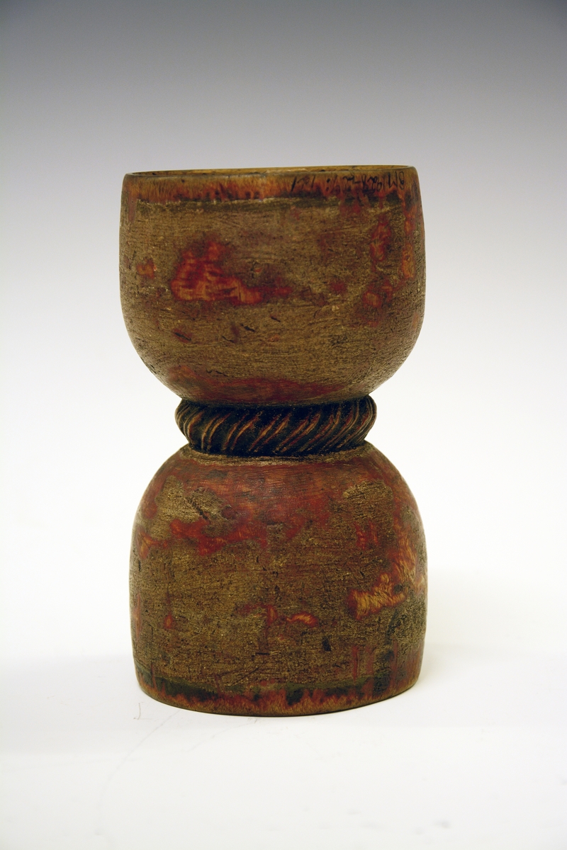 Dobbeltbeger. Fra protokollen: Bugge svarva av bjørk, maala. Baae staupi av paa lag same storleik, innsnørde med eit toglaga band. Utanpaa er den graa-raude maalingi noko avsliti, inni er rosemaala paa gul grunn med raude og grøne rosur, svart konturer. I det eine staupet er ein liten raud botnblom, og fraa denne gjeng mjuke rislur med tytebærblad paa. Kring tromi inni denne innskrift: "Bugen bruges i Fleng af Pige og Dreng". I det hitt staupet er maala eit stort firblad danna av 4 tulipanlaga blomar ut fraa ein botnblom. Millom tulipanane tytebærblad. Innskrift kring tromi inni "O.A.S.M. ANNO 1766"