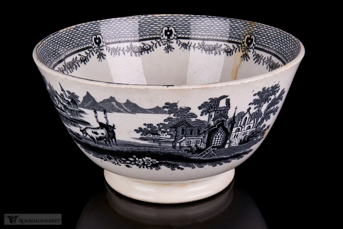 Innvendig et landskap med en klosterruin, hus og vegetasjon med vann rundt, og to kyr i forkant. På bollens sider er det et motiv med bebyggelse på en øy i en innsjø med seilbåter på vannet, fjell i bakgrunnen, og en borg eller landsby og to kyr i forgrunnen. Akantusranker rundt påskriften.