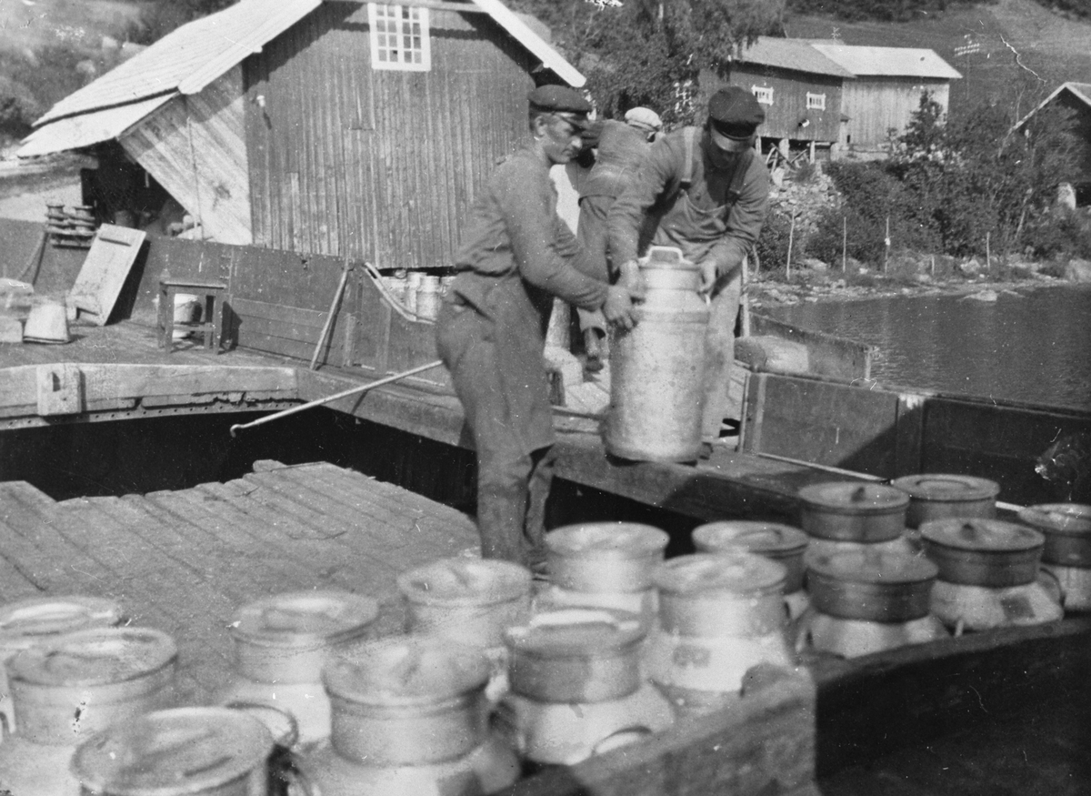 Frakting av melkespann fra Kapp til Hamar ca.1927. Sannsynligvis båten "Haabet" som ligger ved Kapp brygge og laster melkespann som skal til fabrikken på Hamar. Dette var på tiden da Kapp melkefabrikk ble avviklet. Oskar Gjævert tar i mot melkespann fra Martin E. Sandvold. Gjævert var medeier av "Haabet"