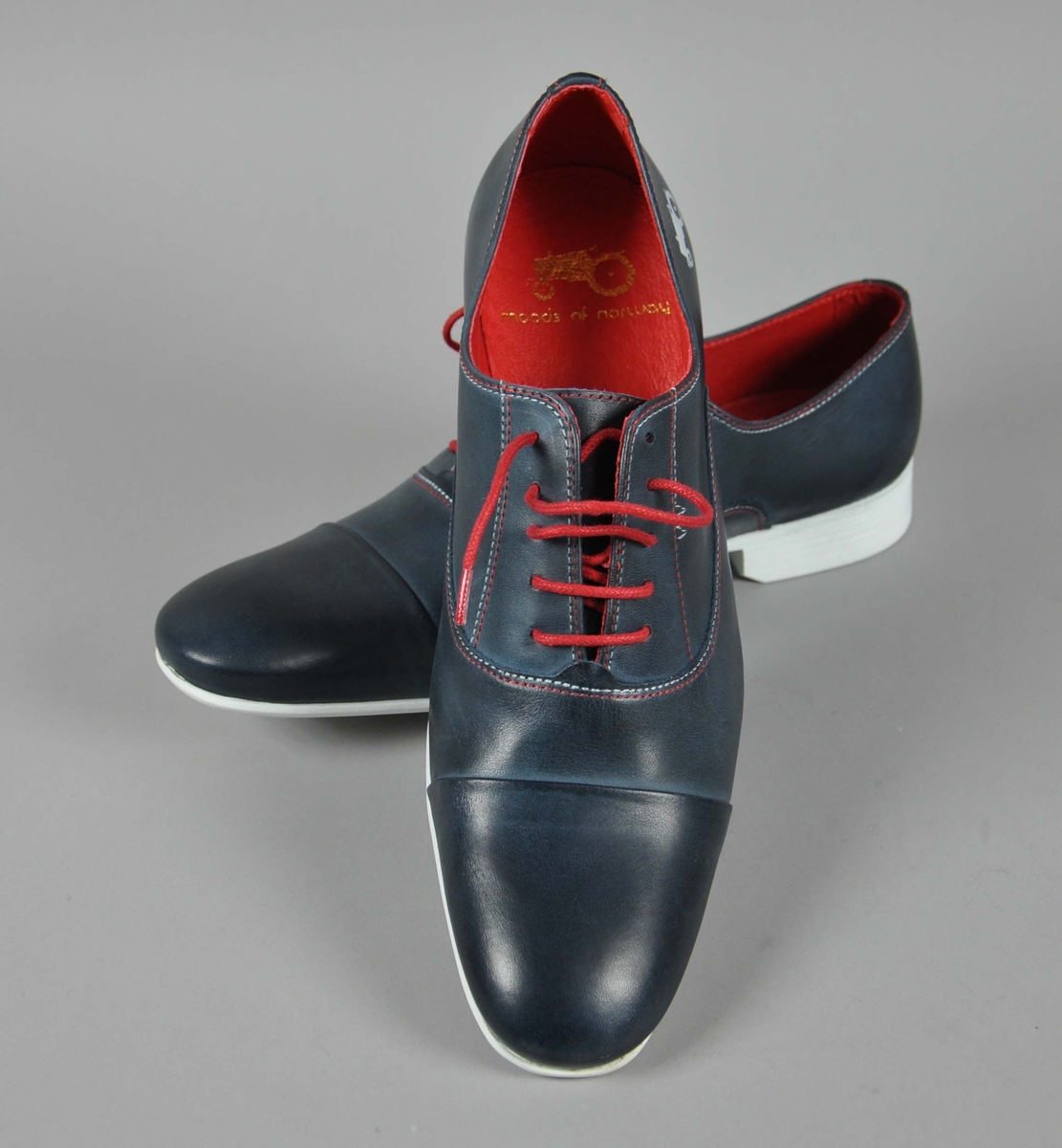 Et par blå skinn herresko i str.42,røde skolisser,røde og hvite sømmer .
Traktor-logoen påtrykt i hvitt på begge skoene.