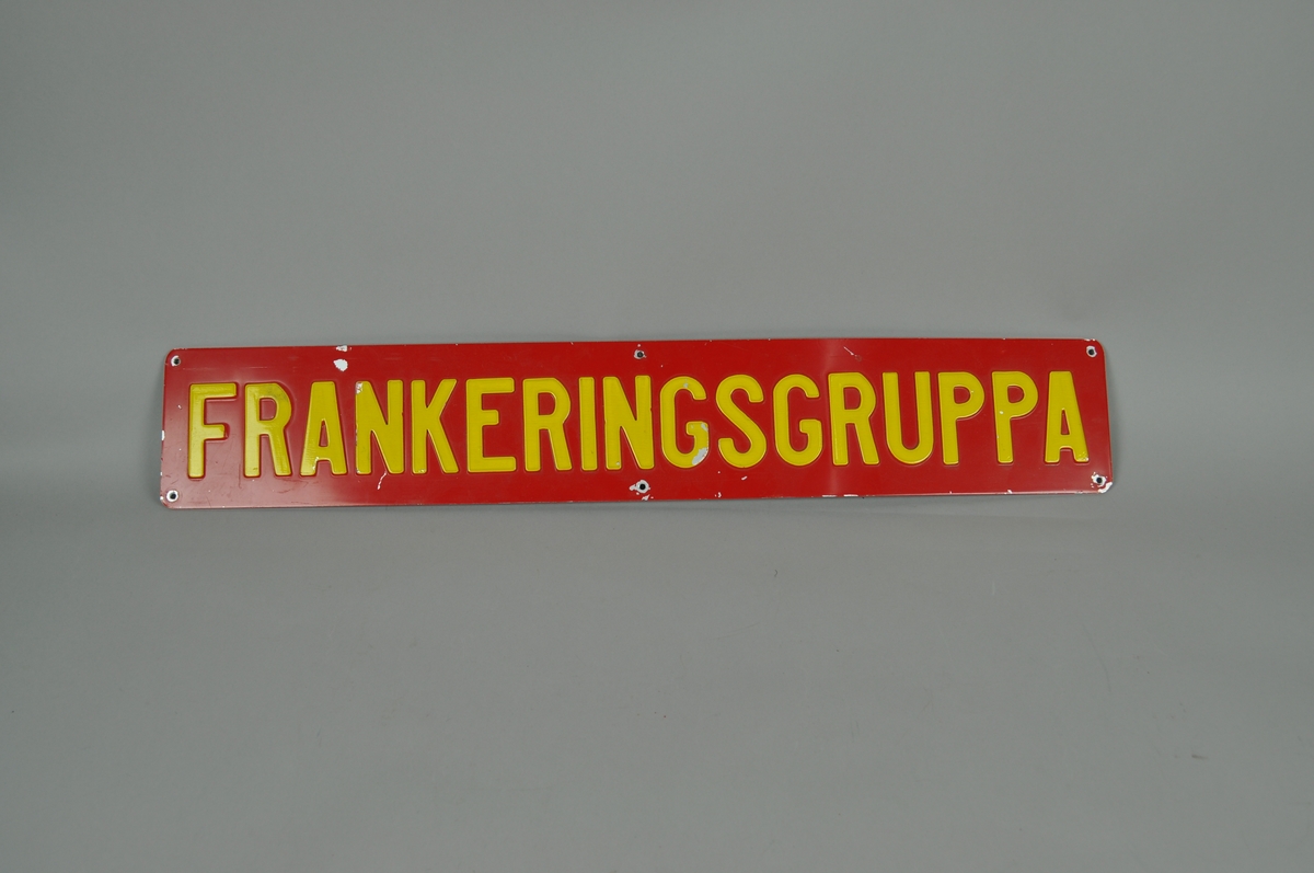 Rektangulært opplysningsskilt med rød bunnfarge og gul skrift merket "FRANKERINGSGRUPPA".