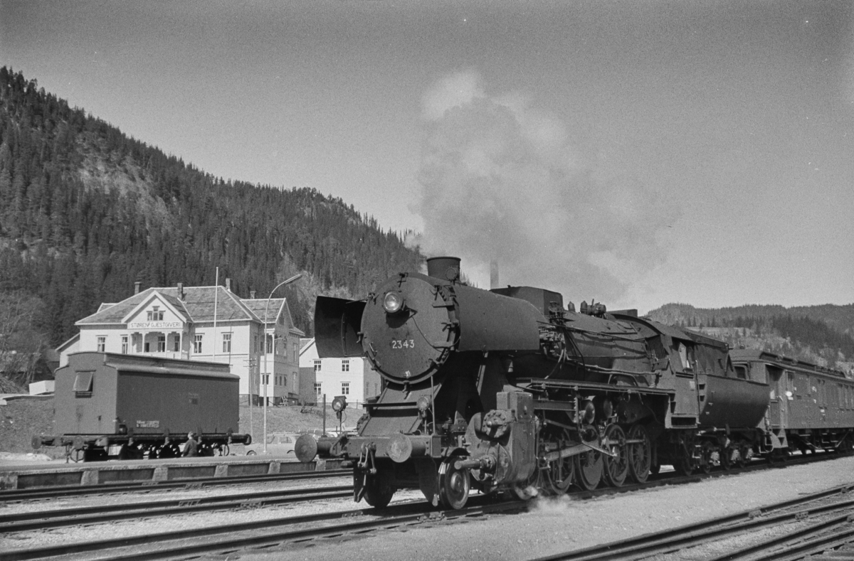 Tog med vogner lastet med pukk på Støren stasjon. Toget er underveis til Dovrebanen. Toget trekkes av damplokomotiv type 63a nr. 2343. I bakgrunnen Støren Gjestgiveri.