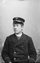 Portrett, ung mann med jernbaneuniform sitter på stol, bryst