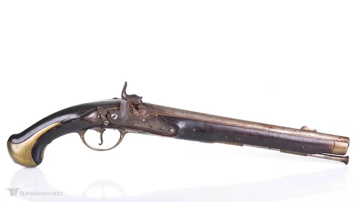 Flintlåspistol med glattboret løp, uten baksikte og med åpent korn. Skjefte av bøk med messingbeslag i enden og ved munningen. To røkner med ladestokk.