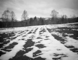 Vårmotiv av jorde, delvis snødekt, med Gausdalsskaret i bakg