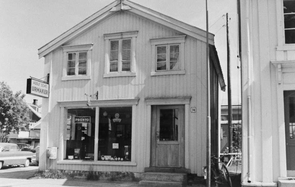 Urmaker Adolf Scheis forretning i Sjøgata 14, ca. 1960. Huset stod tilbaketrukket fra byggelinja med gavlen mot gata. Oppkjøpt og revet som ledd i byggingen av Domus.