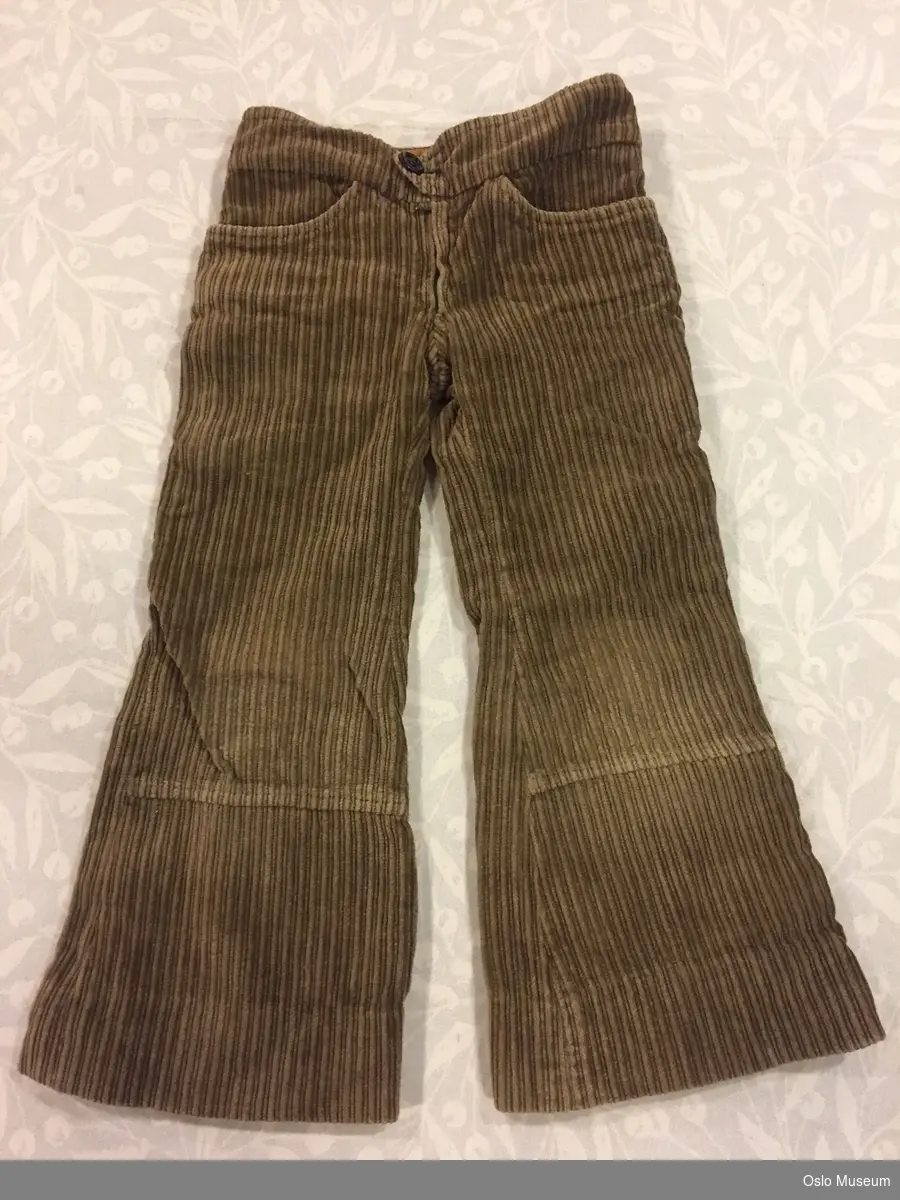 Hjemmesydd bukse i brunt cordfløyelstoff fra 1977/78 med sleng. Barnestørrelse (8-9år).