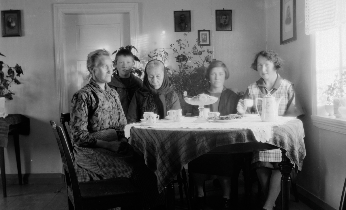 Fire kvinner og en gutt ved kaffebordet innendørs