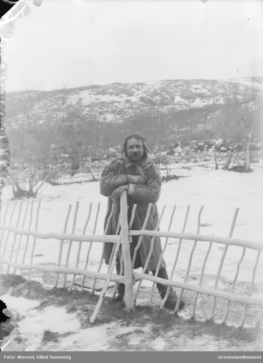 En mann i pesk står ved hagegjerdet på doktorgården Solheim, Kirkenes.