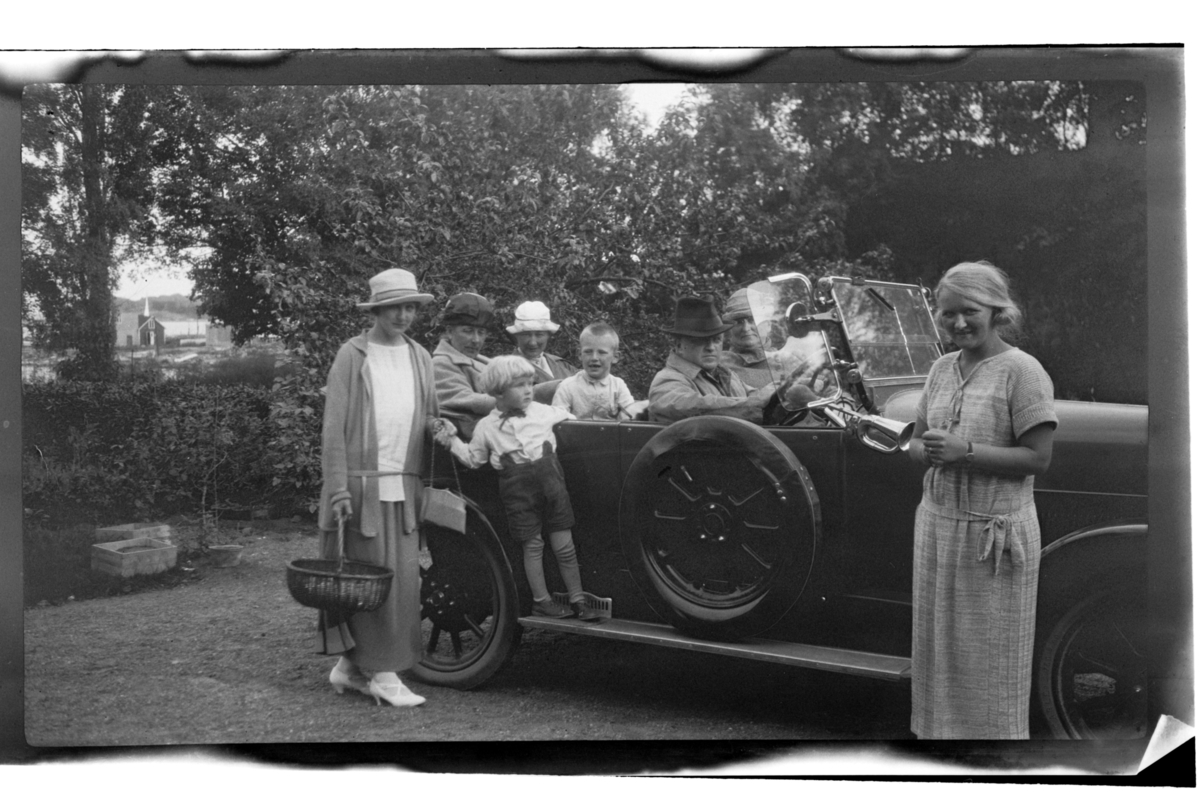 Barn og voksne samlet i og rundt bil ved Stavern. Fra venstre Hilda Sundt, ukjent, Rolf Sundt Jr., Elisabeth (?), Julius og Trygve Sundt, ukjent og Juliue Cecilie (Essemor) Sundt i bilen. Fotografert 1925.