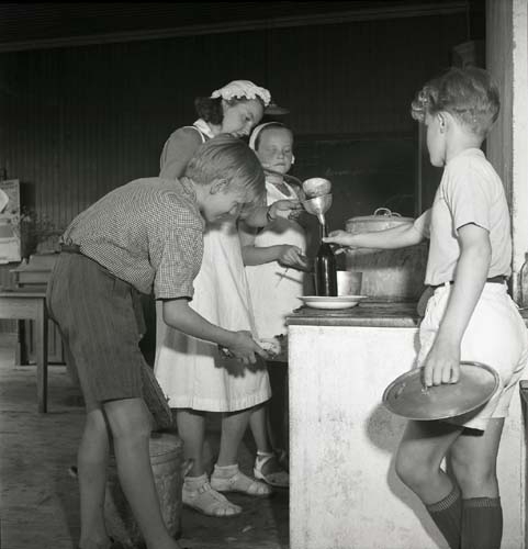 En vuxen och några barn kokar saft och häller på flaska. Från Unga Odlares klubbodlingar, 1948.