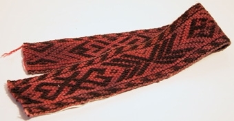 Bandprov av pälsskärp, rött och mörkbrunt med plockat mönster.