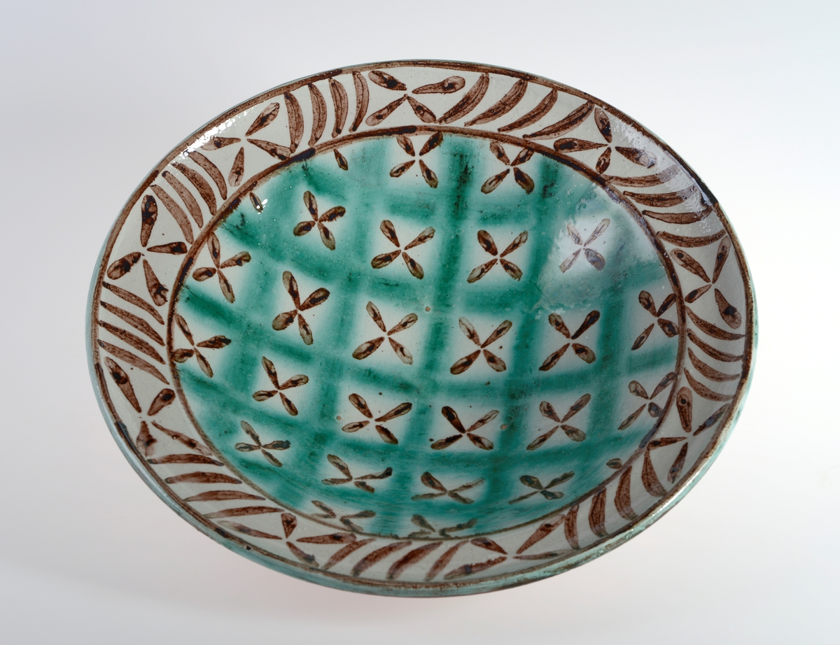 Sirkulær skål av leirtøy med glasur og håndmalt geomertrisk mønster som dekorasjon. Kan ha blitt brukt som både pyntegjenstand og bruksgjenstand.