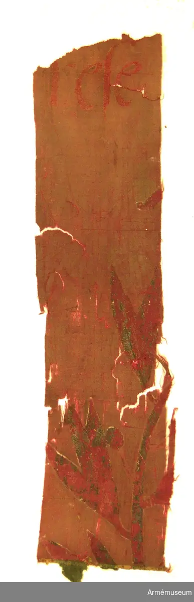 Fragment av duk av sidentaft med rutor i rött och grönt.

Två långsmala remsor, 1400 x 80 mm.

Två andra fragment finns av fanan, båda med separata accessionsnummer:
AM.068250 samt AM.068251.