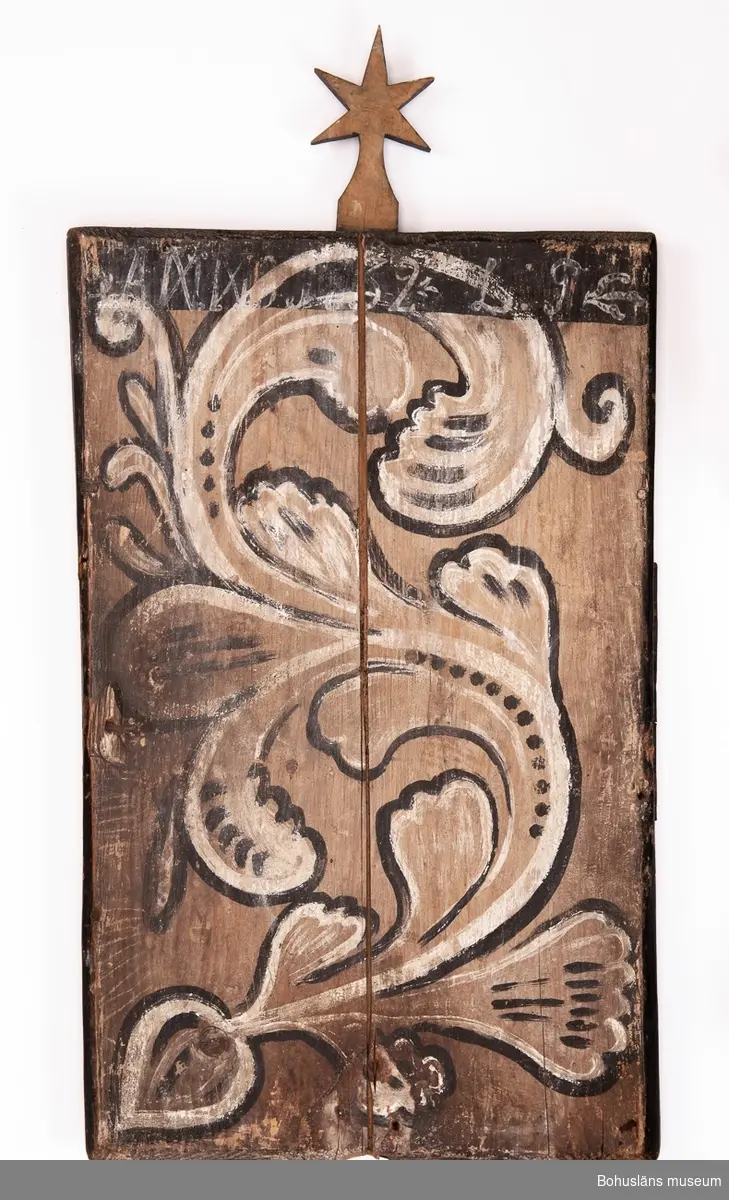 Psalmnummertavla av trä för att hänga upp nummer på psalmer som ska sjungas under en gudstjänst. Framsidan hopfogade svartmålade trädelar, överst målat "No", inramat av en ockragul målad ram. Krön bestående av sexuddig stjärna.
På baksidan ett limfärgsmåleri, barockdekor i form av en akantusslinga. I övre kanten målat "ANNO 1732 L : P".
Ur handskrivna katalogen 1957-1958:
Nummertavla 1732 Lane Ryr
H, utan stjärnan: 62,5 cm. Br. 39 cm; trä, profil. ramlist, upptill 6-uddig stjärna. 
6 tillk. siffror av bly, vitmålade, etta, tvåa, trea, fyra, femma, sjua, nr 405 b - 405 g. Föremålen oskadade.