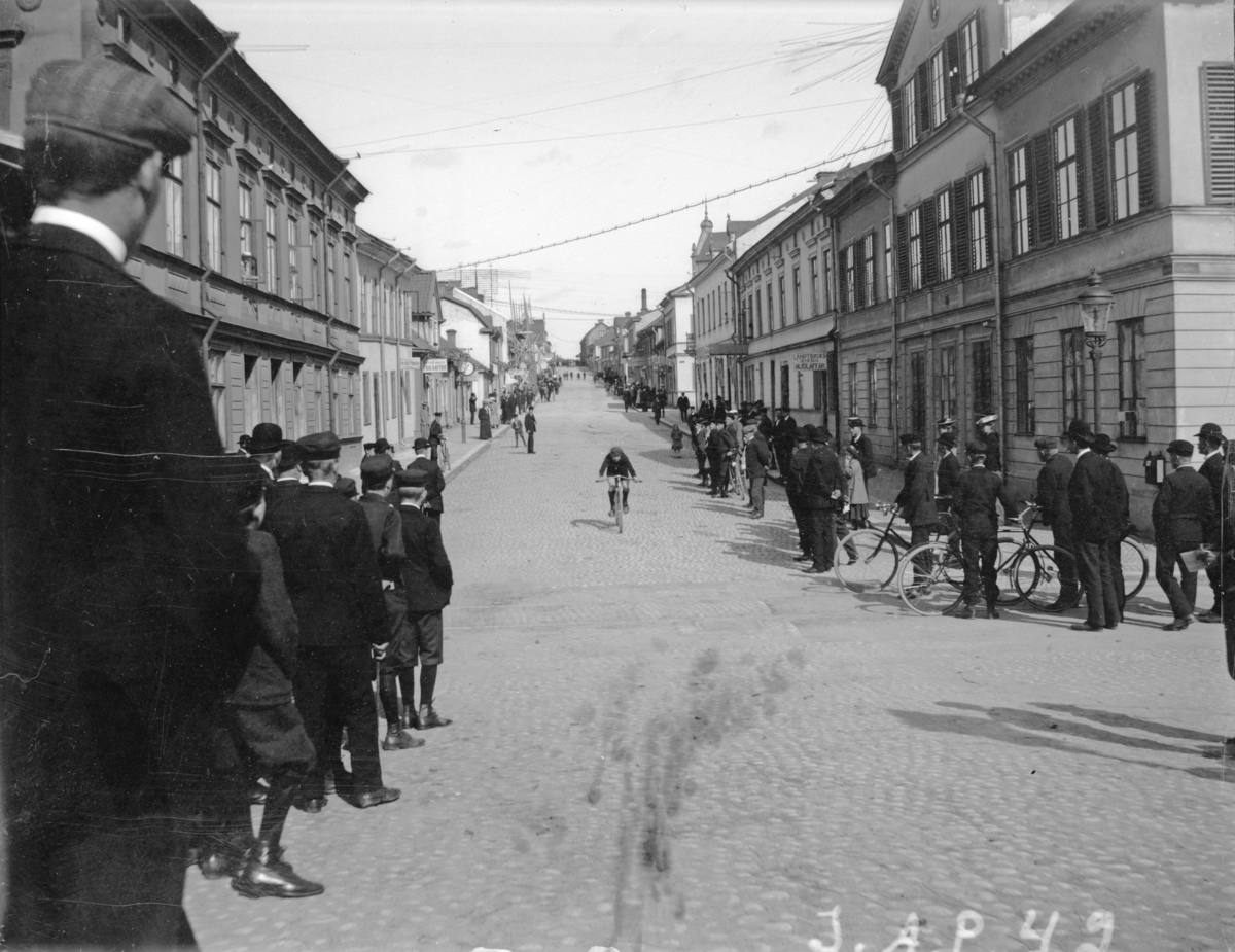 "Mälaren runt". Cyklist färdandes nedför Kungsgatan, sett nedifrån Ågatan, Enköping.