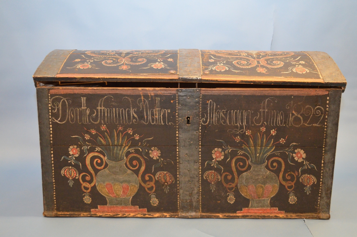 Rosemåla kiste med blomar, rankar, urner, prikkar og skrift. Påført skrift seier: Dortte Amunds Datter Mosagger Anno 1822.