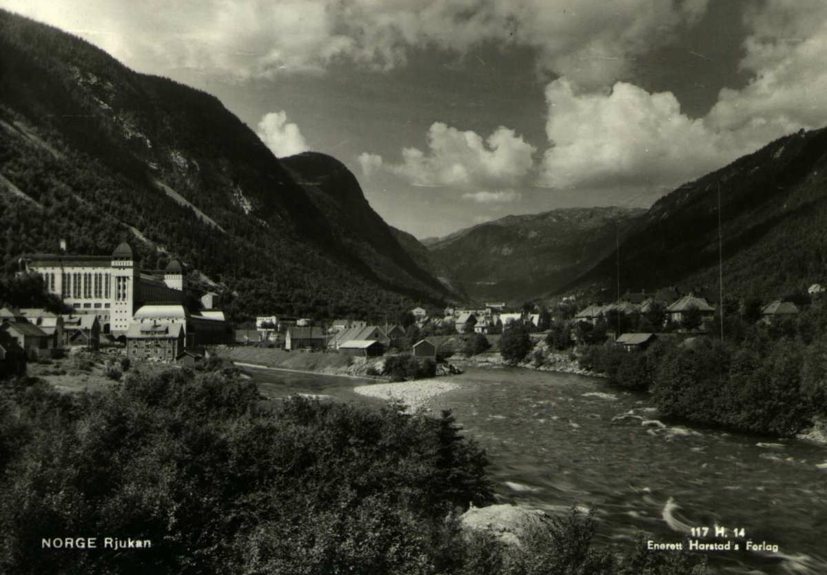 Postkort. Fotografisk motiv. Svart/hvitt. Oversiktsbilde. Motiv fra Rjukan. Bybebyggelse. Elv. Fjell. Stemplet 23.08.1946.