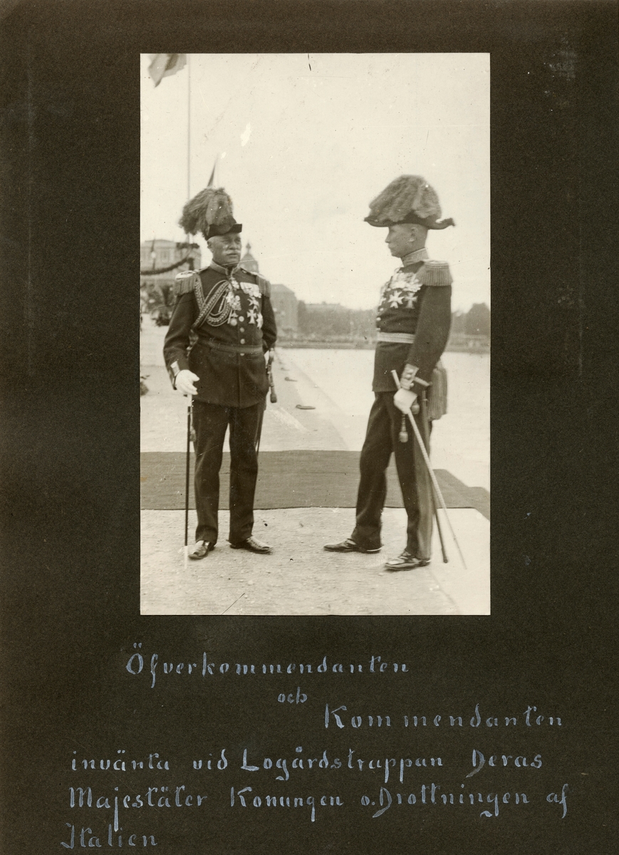 Text i fotoalbum:  "Öfverkommendanten och Kommendanten (Carl Ankarcrona ) invänta vid Logårdstrappan Deras Majestäter Konungen o. Drottningen af Italien”.