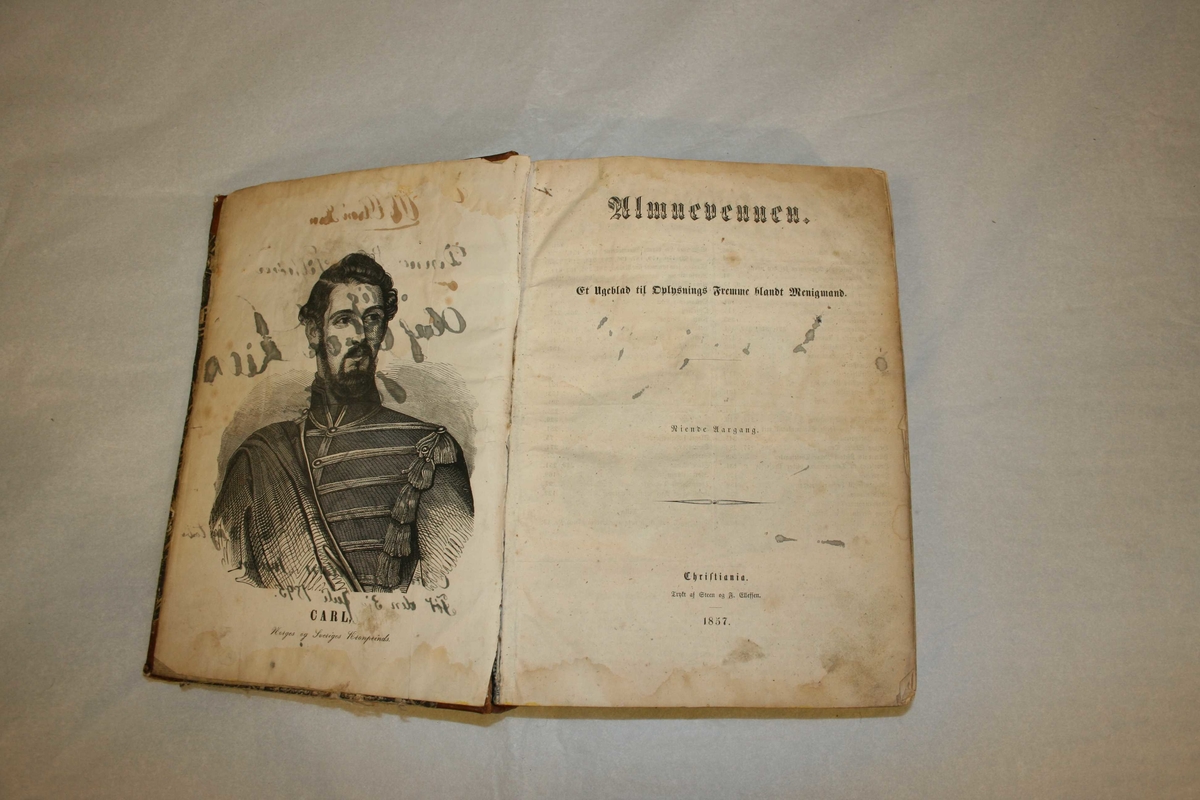 Rektangulær bok med stive permar. Almuevennen frå 1854 og 1857, pluss Adressebladet 1857.
