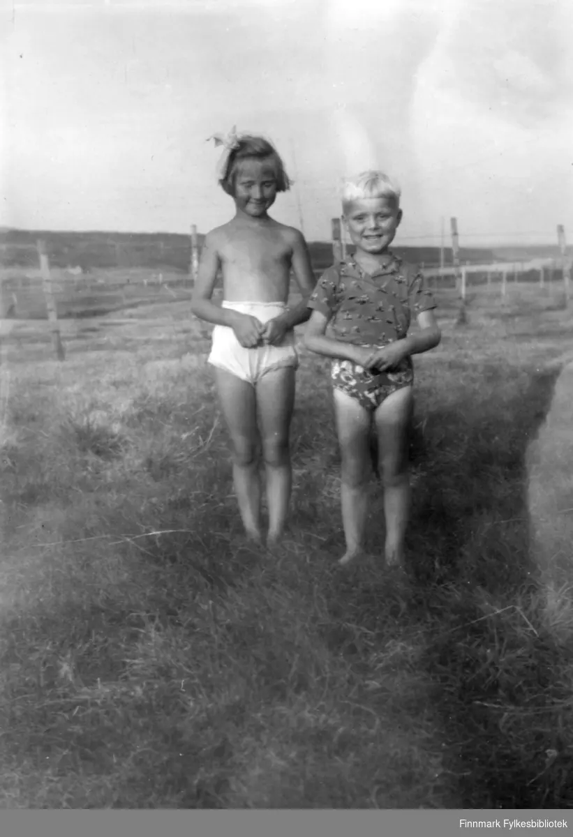 Sommerbilde med to barn som står i gresset. Familiealbum tilhørende familien Klemetsen. Utlånt av Trygve Klemetsen. Periode: 1930-1960.
