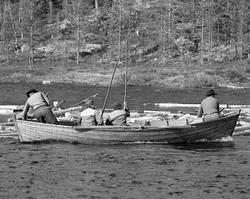 Båtlaget til Ivar Graff ved en tømmerhaug som hadde bygd seg
