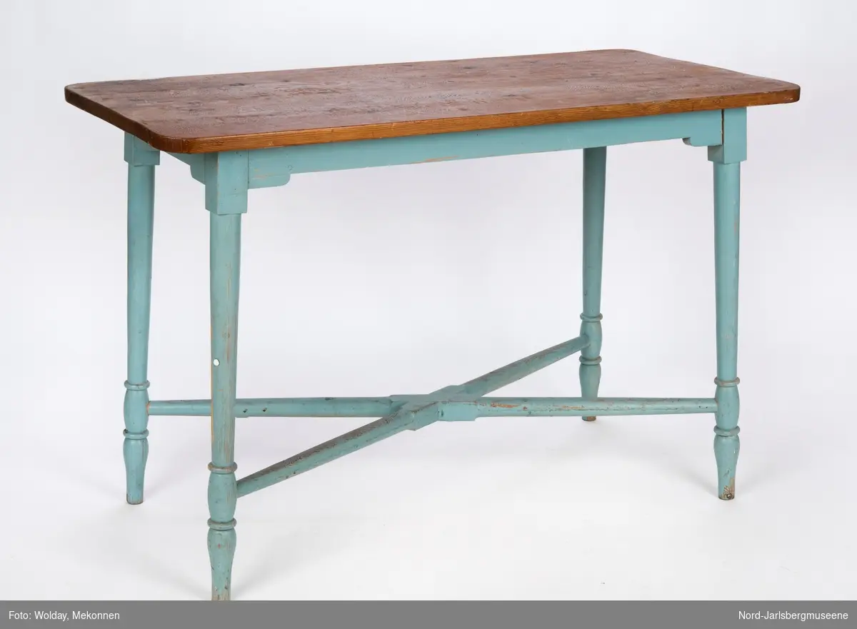 Et bord, kjøkkenbordtype, med lakkert bordplate og blåmalte ben og understell. Bena har dreid dekor, og er stabilisert ved et kryssverk nederst mellom de fire bena.