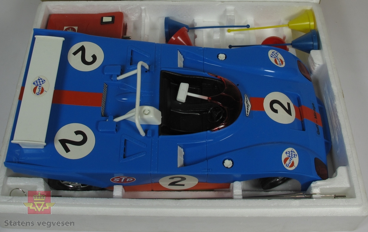 Miniatyr, lekebil i eske. Laget hovedsakelig av plast med eske av papp. Blå bil i blå og hvit eske. Skala 1:10. Batteridrevet fjernkontroll.