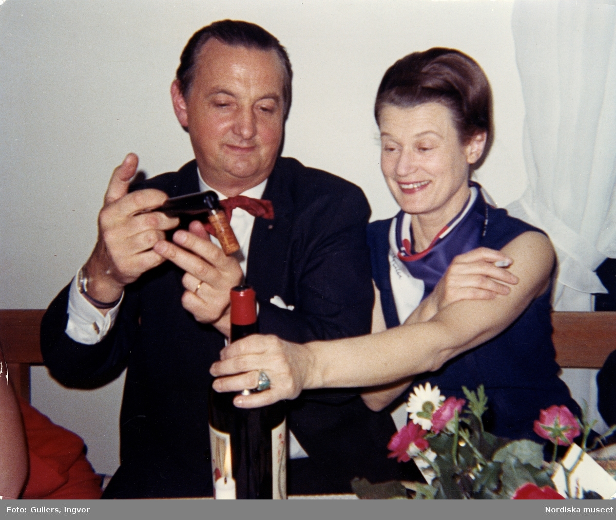Fotograferna KW Gullers och Kerstin Bernhard i färd med att öppna en vinflaska vid en middag