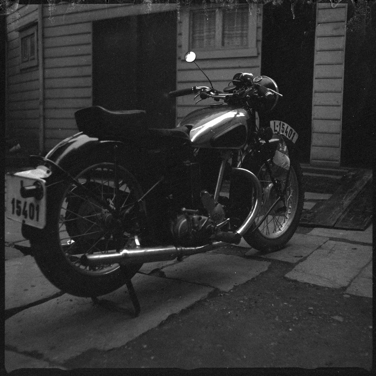 En motorsykkel av merket "Calthorpe" fotografert i en bakgård.