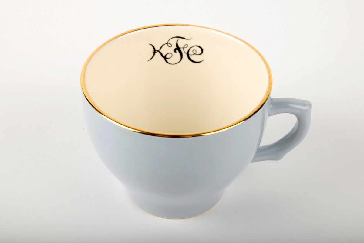 Kaffekopp med fat.

Koppen har monogram på innsiden. Både koppen og fatet har gullfarget kant.