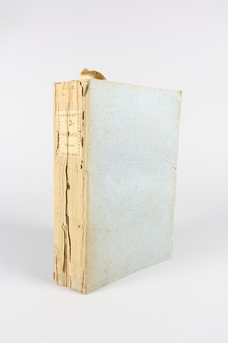 Bok, häftad,"Oeuvres complètes de Voltaire", del 12, tryckt 1785.
Pärm av gråblått papper, på pärmens baksida klistrad sida ur annan bok. Med skurna snitt. På ryggen klistrad pappersetikett med tryckt text samt volymens nummer. Ryggen blekt.