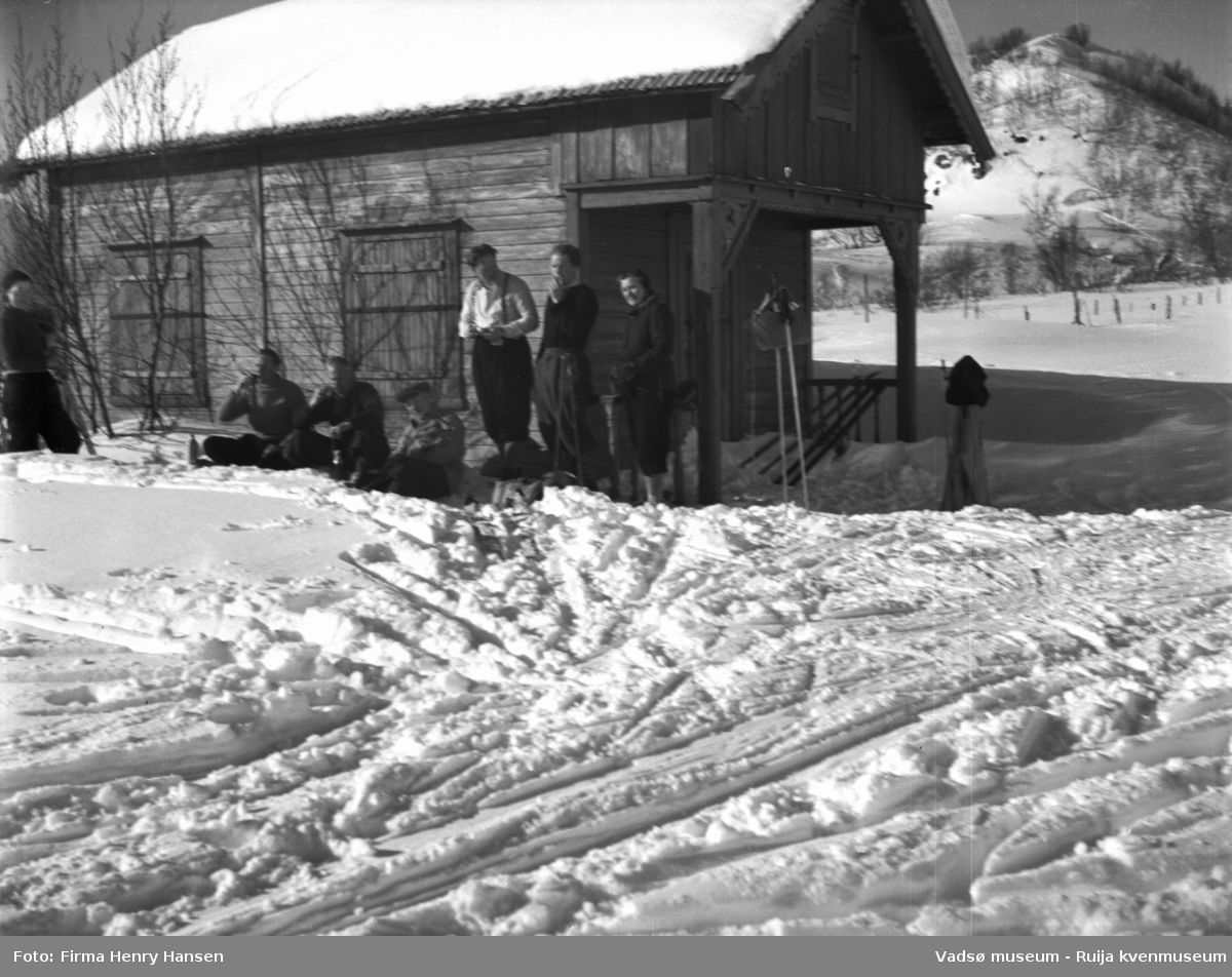 Vinikka. Vinterlandskap. Skiløpere raster foran en hytte.