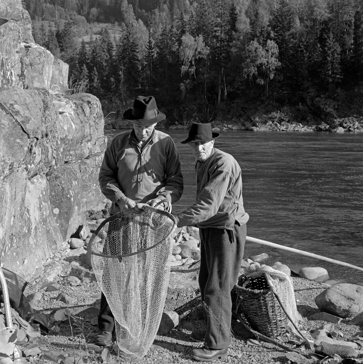 Lågåsildfiskerne Ole Haugen (1912-1982) og Arne O. Haugen (1883-1974), Oles far), fotografert ved bredden av Gudbrandsdalslågen, der de var i ferd med å binde «hugguet» på «rauna» (skaftet) til en stokkehåv.  Rauna var lagd av langsomtvokst, seig tennargran.  På stokkehåver brukte rauna å være 6,5 til 8,5 meter lang.  Håvhugguet ble lagd av grankvister  med litt stammeved i endene.  Denne stammeveden som ble brukt som anlegg på enden av rauna.  Kvistene ble bøyt mot hverandre, slik at de dannet ei bøyle, som «påsan» kunne bindes på.  Sammenføyinga ble gjort ved hjelp av et par spikere og påsurret tau eller, som her, splittet bambus.  Påsan var et nett, bundet av lin.   Bak karene ser vi et flettet bæreredskap, en såkalt «snik», som ble brukt som beholder for fangsten.   Både far og sønn Haugen var kledd i vadmelsbukser og busserull, og de brukte svarte, vidbremmete hatter som hodeplagg.

Stokkehåven ble brukt fra en båt - ei «åfløy» - som var forankret i en stokk, som i sin tur var festet i stein i elveløpet.  Deler av fiskeribiologen Hartvig Huitfedt-Kaas' beskrivelse av håvene og stokkhåvfisket fra 1917 er gjengitt under fanen «Opplysninger».