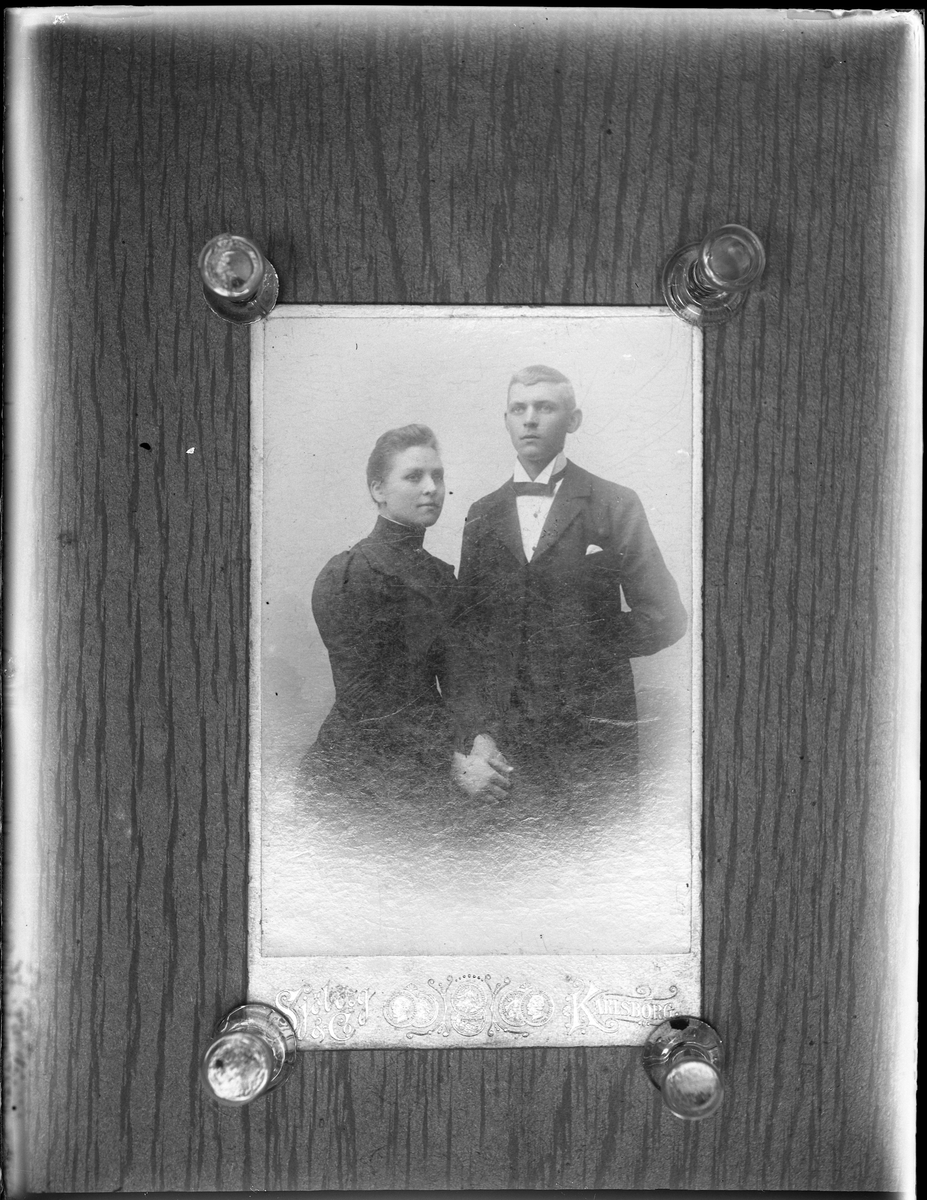 Reprofotografi av ett porträtt på en man och en kvinna. Båda är klädda i svart, hon sitter ned medan han står lite bakom henne.